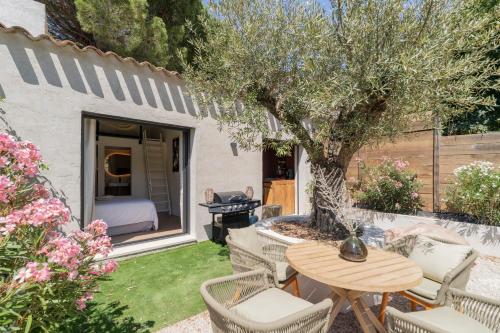 a patio with a table and chairs and a tree at L'hôtel des oiseaux in Les Baux-de-Provence