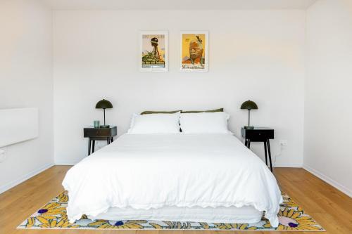 a white bedroom with a white bed and two tables at The Albert Studio in Albert Town