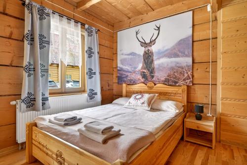 a bedroom with a bed with a deer painting on the wall at Domek u Świerków 2 - Zabytkowe domki 4 do 8 osób i apartamenty z aneksem kuchennym, 1,5km Termy Chochołowskie in Chochołów