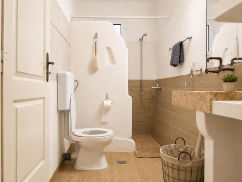 a white bathroom with a toilet and a sink at The simple two-bedroom house at Klima Beach in Samos
