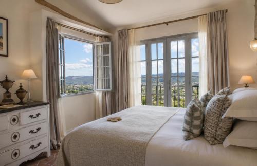 a bedroom with a bed and a large window at Hotel Le Saint Paul in Saint Paul de Vence