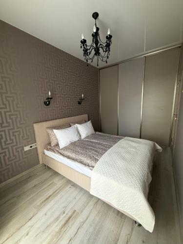 a bedroom with a large bed and a chandelier at Lielais prospekts 54 in Ventspils