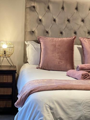 a bed with pink and white pillows on it at Luxury Apartment Overlooking the River in Midrand