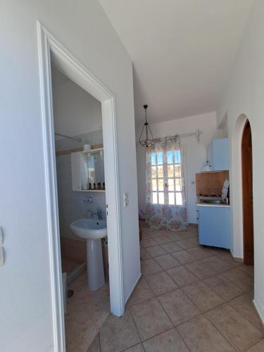 a bathroom with a sink and a mirror and a kitchen at Hotel Posidonion in Koufonisia