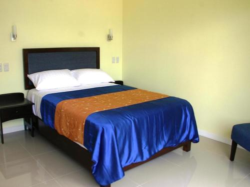 a bedroom with a bed with a blue and orange blanket at Caimito Beach Hotel in Ichon