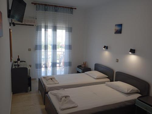 two beds in a room with a window at Dina Apartments Kokkari, Pension Dina, Dina Rooms in Kokkari