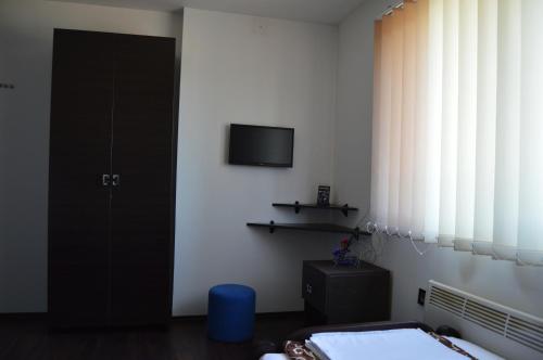 a bedroom with a bed and a tv on the wall at Guest House Vila Salute in Niš