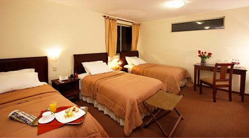 una habitación de hotel con 2 camas y una mesa con una bandeja de comida en Hotel San Sebastián Loja en Loja