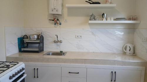 a white kitchen with a sink and a stove at Acacia Nest in Tangier