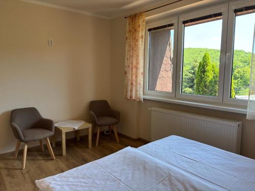 a bedroom with two chairs and a bed and a window at ubytovanie Vážka in Banská Štiavnica
