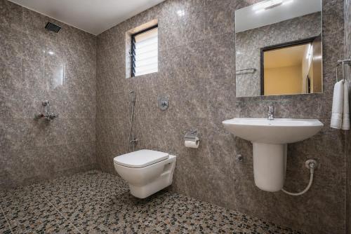 a bathroom with a toilet and a sink and a mirror at Vinsons Cottages in Colva