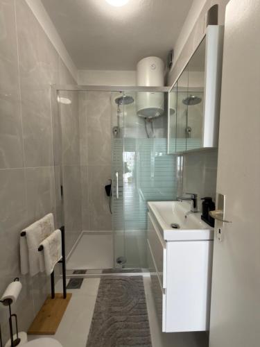 a white bathroom with a shower and a sink at Apartments Derado in Supetar