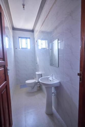 a white bathroom with a toilet and a sink at Talia holiday home ,Malindi kenya -1 in Malindi