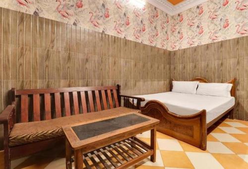a bedroom with a bed and a bench and a wall at Hotel New Lucknow in Lucknow