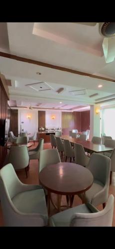 a waiting room with tables and chairs in a building at Emerald Inn in Islamabad