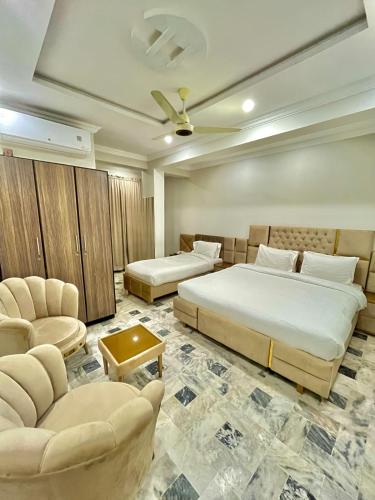 a hotel room with two beds and two chairs at Emerald Inn in Islamabad