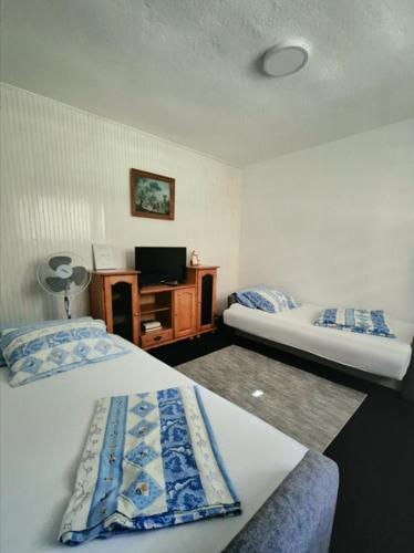 a hotel room with two beds and a tv at Rooms-Zejnep SARAJEVO in Sarajevo