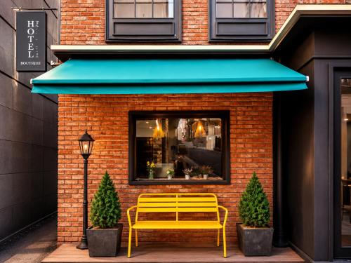 a yellow bench sitting in front of a building at SR Compact Hotel Sinchon in Seoul