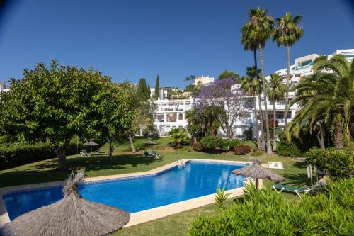 a swimming pool with umbrellas in a resort at appartement gelegen aan de golfbaan op La Quinta Benahavis Marbella in Benahavís