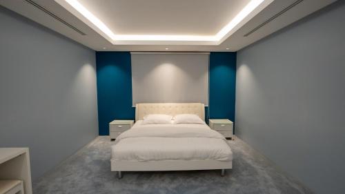 a bedroom with a white bed in a blue wall at شالية 280 in Dammam
