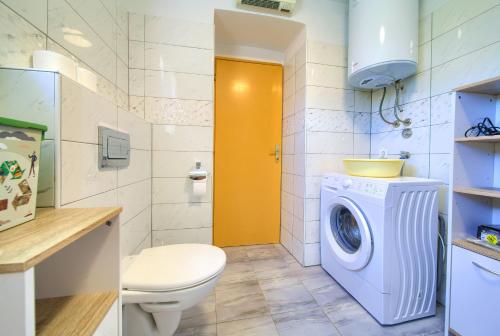 a bathroom with a washing machine and a toilet at Kuca za odmor Kornic in Kornić