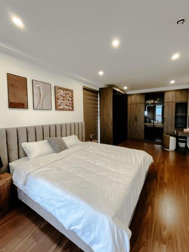a large white bed in a bedroom with wooden floors at Sky villas with large balcony in Hanoi