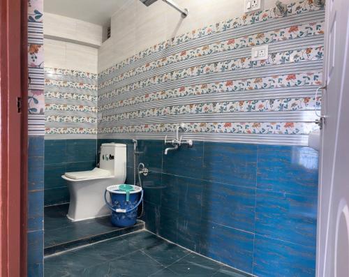 a bathroom with a toilet and a blue tiled wall at The Dusk Stay in Sonāda