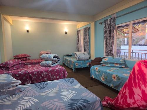 a room with three beds and two chairs and a window at The Dusk Stay in Sonāda
