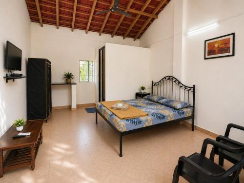 a bedroom with a bed and a table in a room at Vinsons Cottages in Colva
