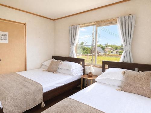 two beds in a room with a window at Biwa 広々テラス bbq 無料駐車場 湖まで徒歩3分 in Takashima