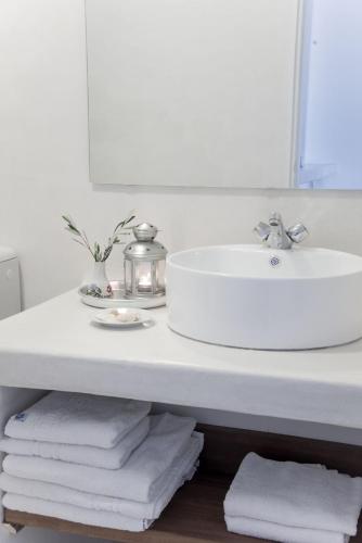 a bathroom with a sink and a pile of towels at White Blue Villa formerly Ippocampi in Koutouloufari
