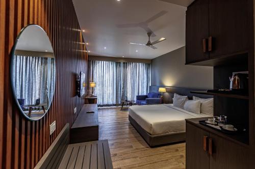 a hotel room with a bed and a mirror at The Democracy Hotel & Resorts Convention Center in Nashik