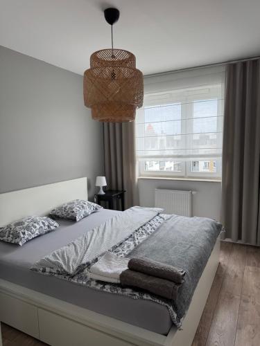 a white bedroom with a bed and a window at Di Trevi Apartment in Wrocław