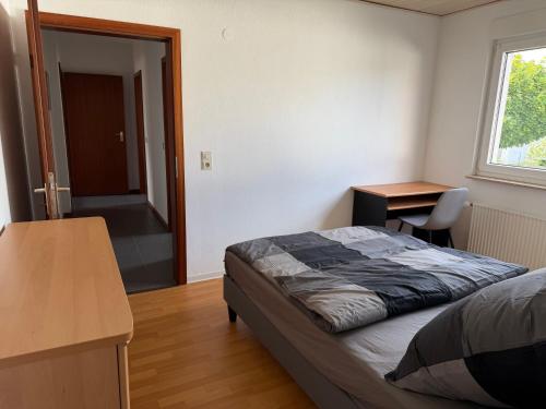 a bedroom with a bed and a desk and a window at Zimmer im Erdgeschoß mit Bad und Küche in Minden