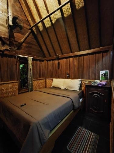 a bedroom with a bed in a wooden room at Tetebatu Valley Bungalows in Tetebatu