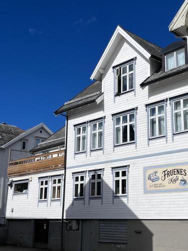 a white building with windows on a street at Fruenes in Volda