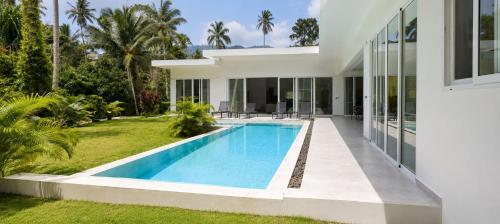 a villa with a swimming pool in front of a house at villa Samuel in Koh Samui
