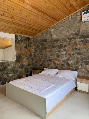 a bed in a room with a stone wall at Perseku GuestHouse in Shirokë