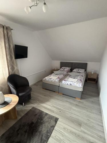 a bedroom with two beds and a chair and a table at Maziarówka in Basznia Dolna