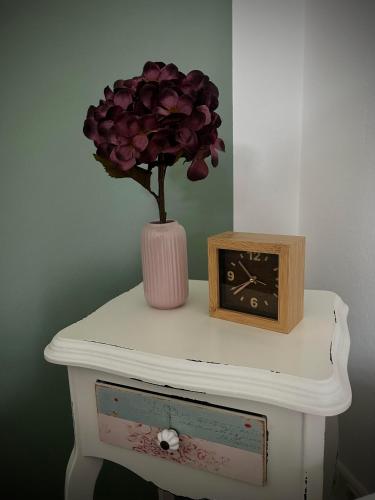 a clock and a flower in a vase on a table at Auszeit in Hasselberg