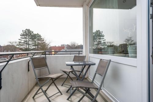 a balcony with three chairs and a table and a window at Hanseatic 208 in Duhnen
