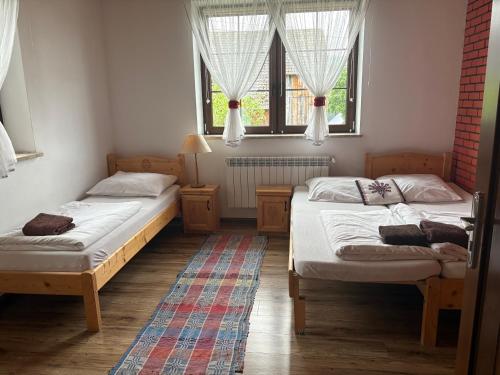 two beds in a room with two windows at Domek pod Majową Górą in Kacwin