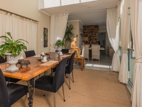 a dining room with a wooden table and black chairs at 78on5th in Hermanus in Hermanus