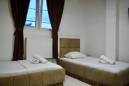 two beds in a room with a window at Hotel Heimli in Prishtinë
