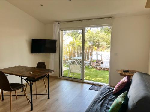 a living room with a couch and a table and a sliding glass door at Hébergement standing au calme in Saint-Maximin-la-Sainte-Baume