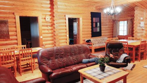 a woman sitting on a leather couch in a log cabin at Loma-Pälsilä lakeside villa in Kuhmoinen