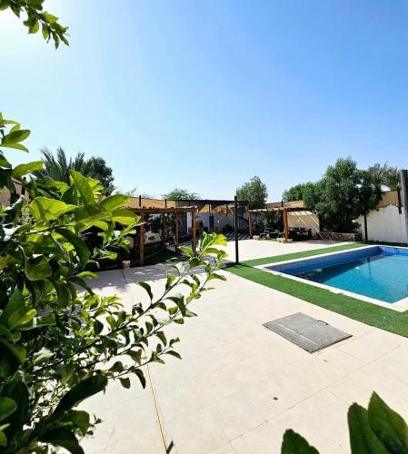 a backyard with a swimming pool and a wooden pergola at Shamsa Chalet in Al Mazār