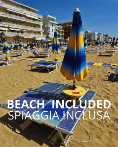 a beach with chairs and an umbrella on the sand at Regina Urban Beach Hotel in Lido di Jesolo