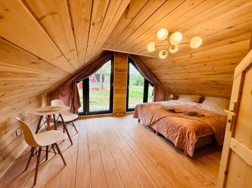 ein Schlafzimmer in einer Blockhütte mit Bett und Stühlen in der Unterkunft Venice barn Przełazy in Przełazy