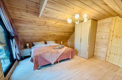 ein Schlafzimmer mit einem Bett in einem Holzzimmer in der Unterkunft Venice barn Przełazy in Przełazy